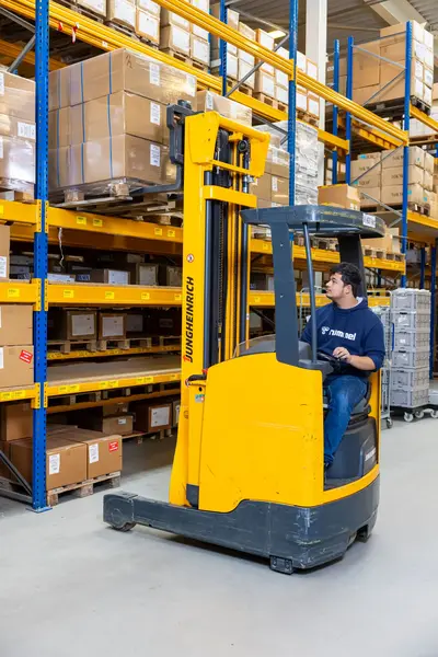 Jongen in vorkheftruck aan het werk in magazijn.