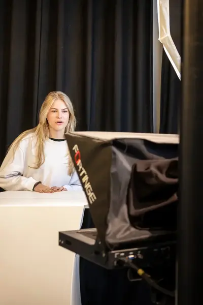Studente filmt een andere studente die achter een spreektafel staat.