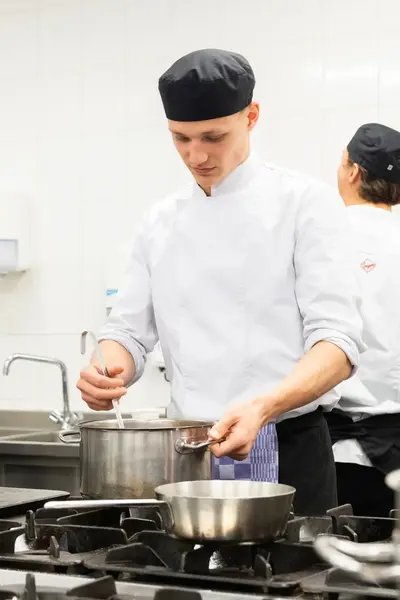Kok werkt geconcentreerd aan een warm gerecht