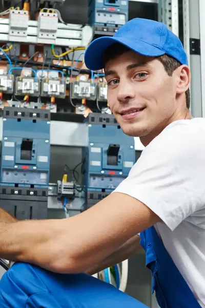 Student voor grote elektriciteitskast en noteert dingen op een blaadje.