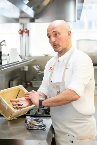 Docent legt in keuken aan student uit hoe je oesters bereidt