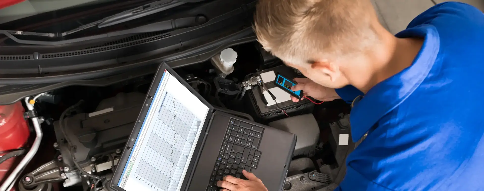 Automonteur met laptop doet metingen onder de motorkap