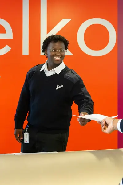 Beveiliger achter balie geeft document aan collega