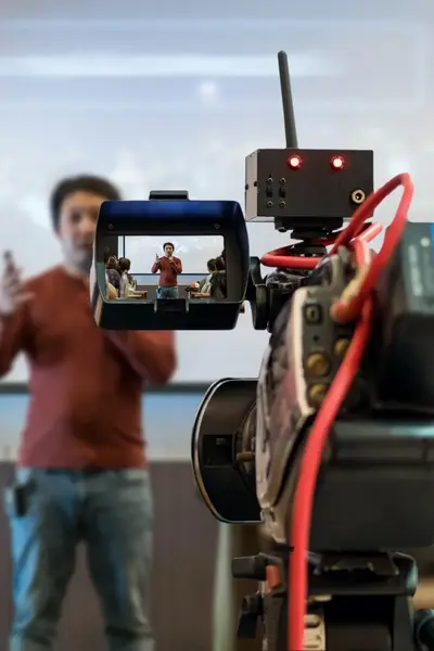 Docent in een klas voor de camera gezien vanuit het standpunt van de camera-operator.