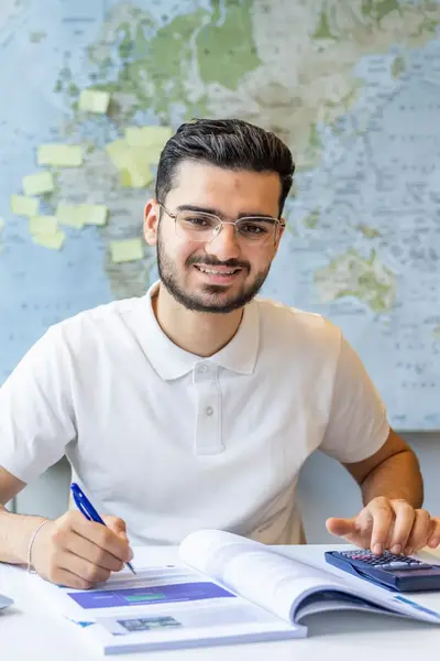 Student werkt aan zijn schoolopdracht met een laptop en rekenmachine.