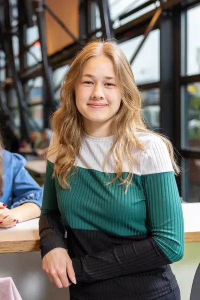 Twee studenten zitten samen in de kantine bij een hoge tafel.