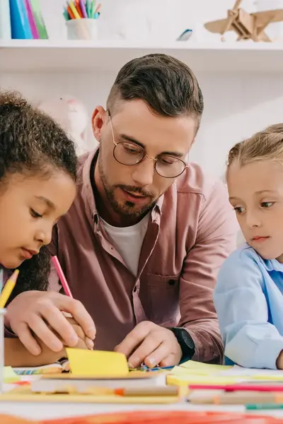 Student kleurt met twee meisjes in kinderopvang of school