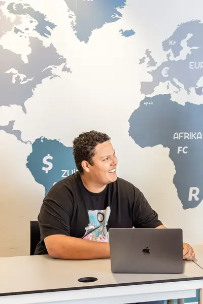 Student met docent zittend achter een laptop voor een monetaire landkaart