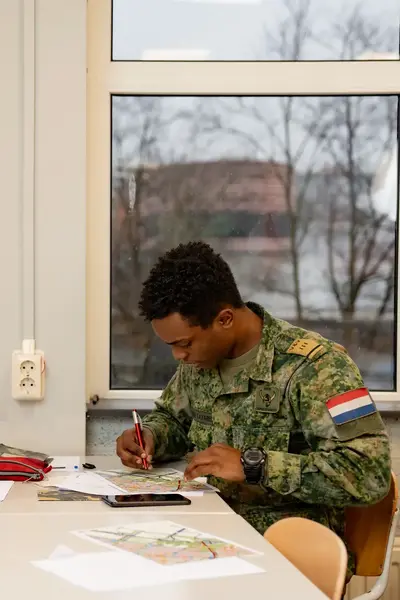 Student Veiligheidscollege in uniform bestudeert landkaart in klas