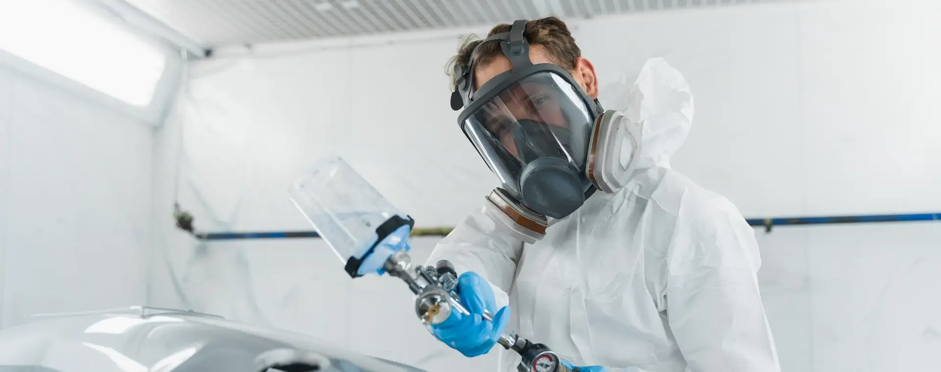 In wit geklede en gemaskerde autospuiter met verfspuit