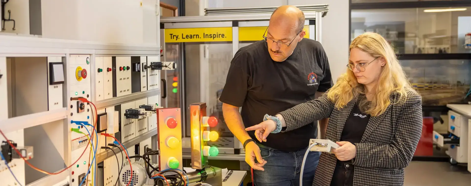 Docent en student met afstandsbediening werken aan een lichtinstallatie