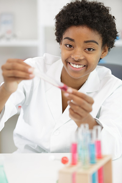 Meisje in witte laboratoriumjas met een reageerbuis in haar hand