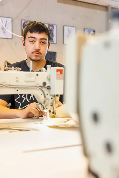 Jonge man achter naaimachine
