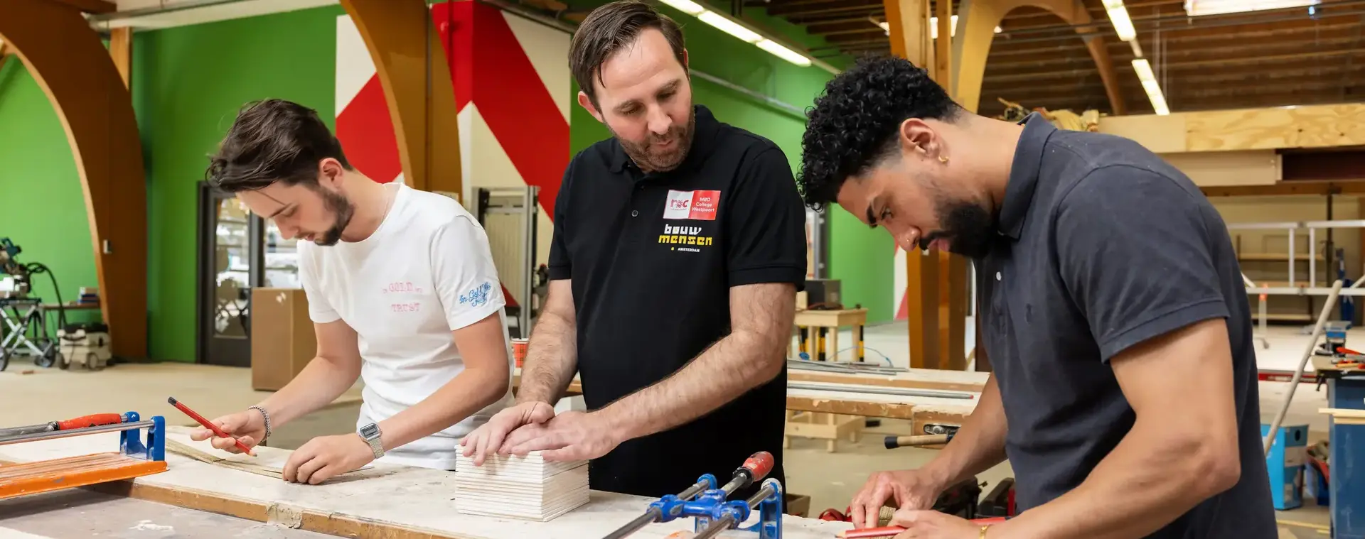 Studenten leren meten en hout bewerken onder begeleiding van een docent