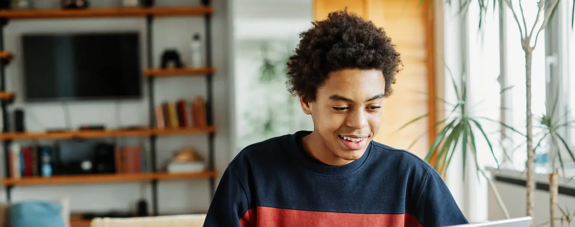 Student werkt thuis aan een opdracht met laptop en schrift.