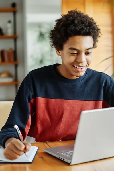 Student werkt thuis aan een opdracht met laptop en schrift.
