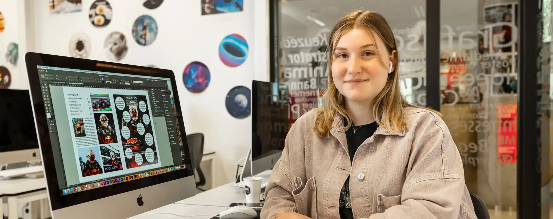 Student zit aan een bureau met een Imac en is media aan het vormgeven.