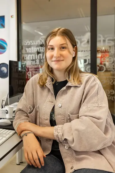 Student zit aan een bureau met een Imac en is media aan het vormgeven.