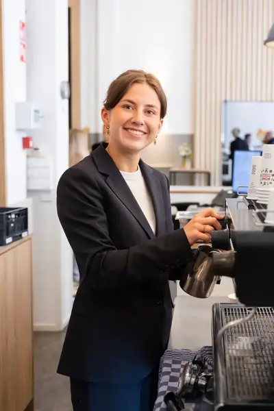Studente Toerisme en Recreatie zet koffie bij koffieautomaat.