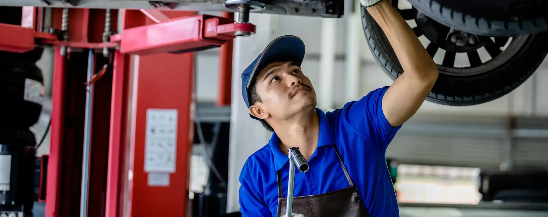 Student werkt onder auto op reparatiebrug