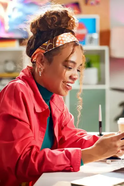 Studente achter bureau kijkend naar haar mobiel.