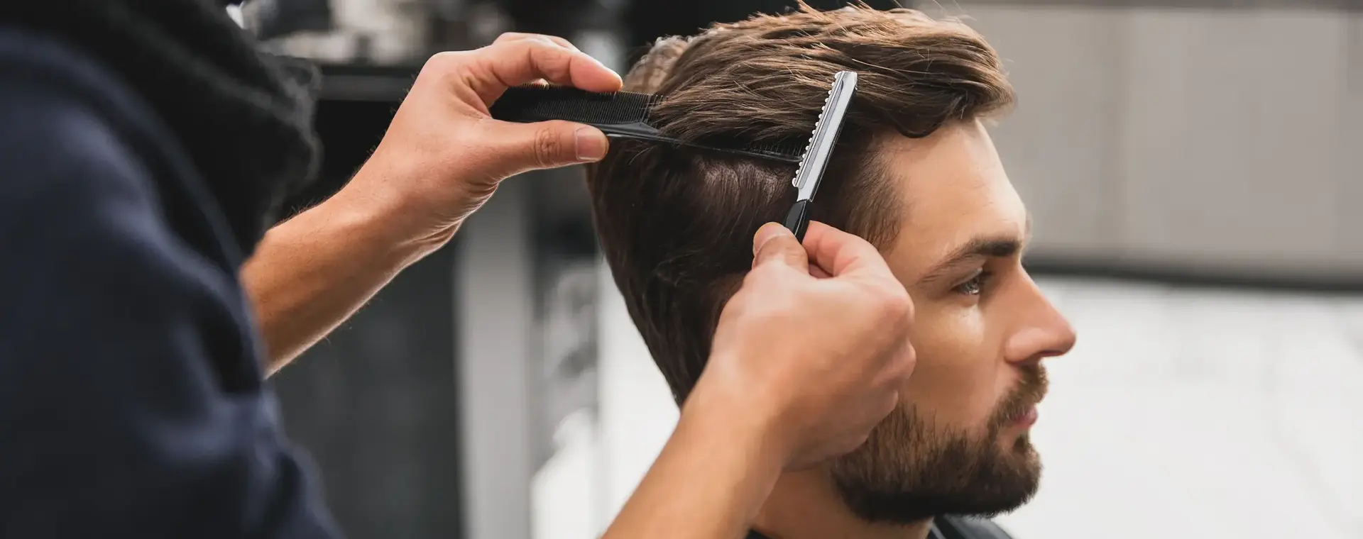 Kapster knipt het haar van een man met een tondeuse en kam in een moderne kapsalon. De klant zit stil terwijl het haar nauwkeurig in model wordt gebracht.