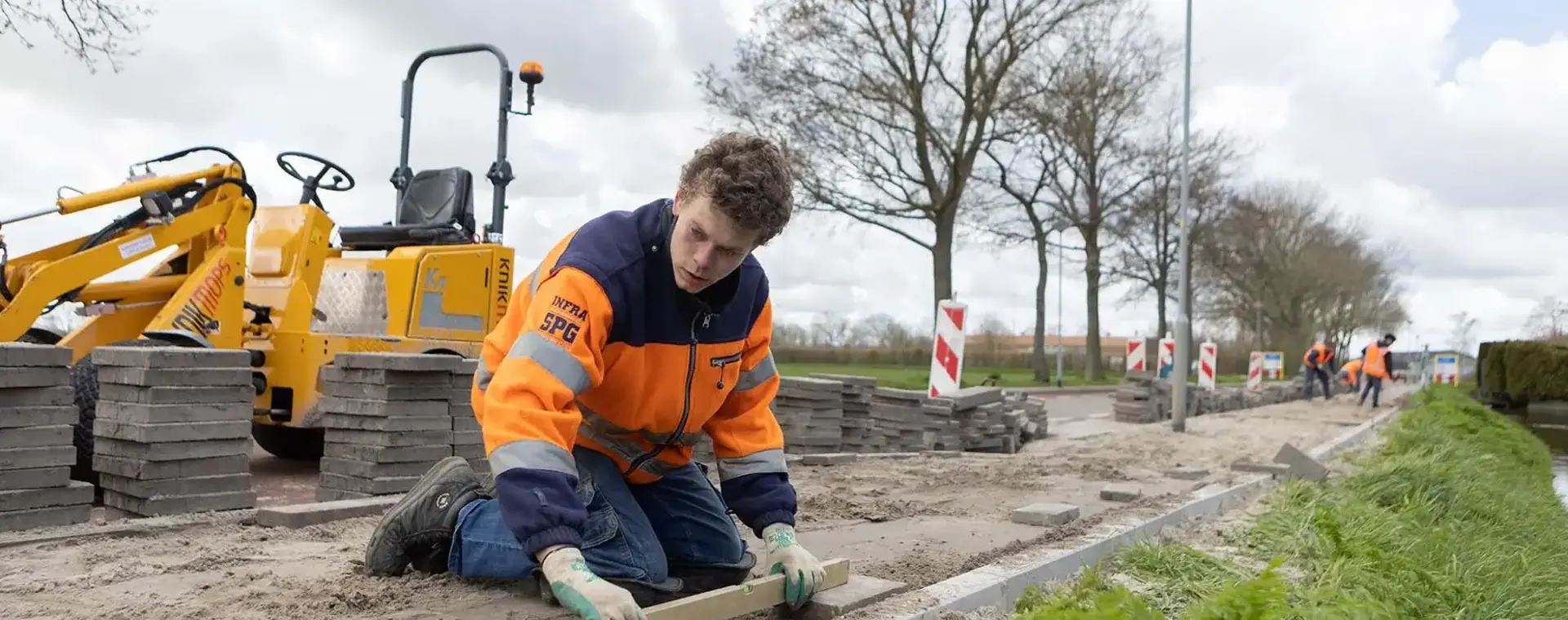 Een jonge man zit op zijn knieën een straat te maken. 
