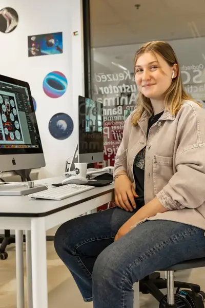 Studente in creative ruimte achter Imac-computer.
