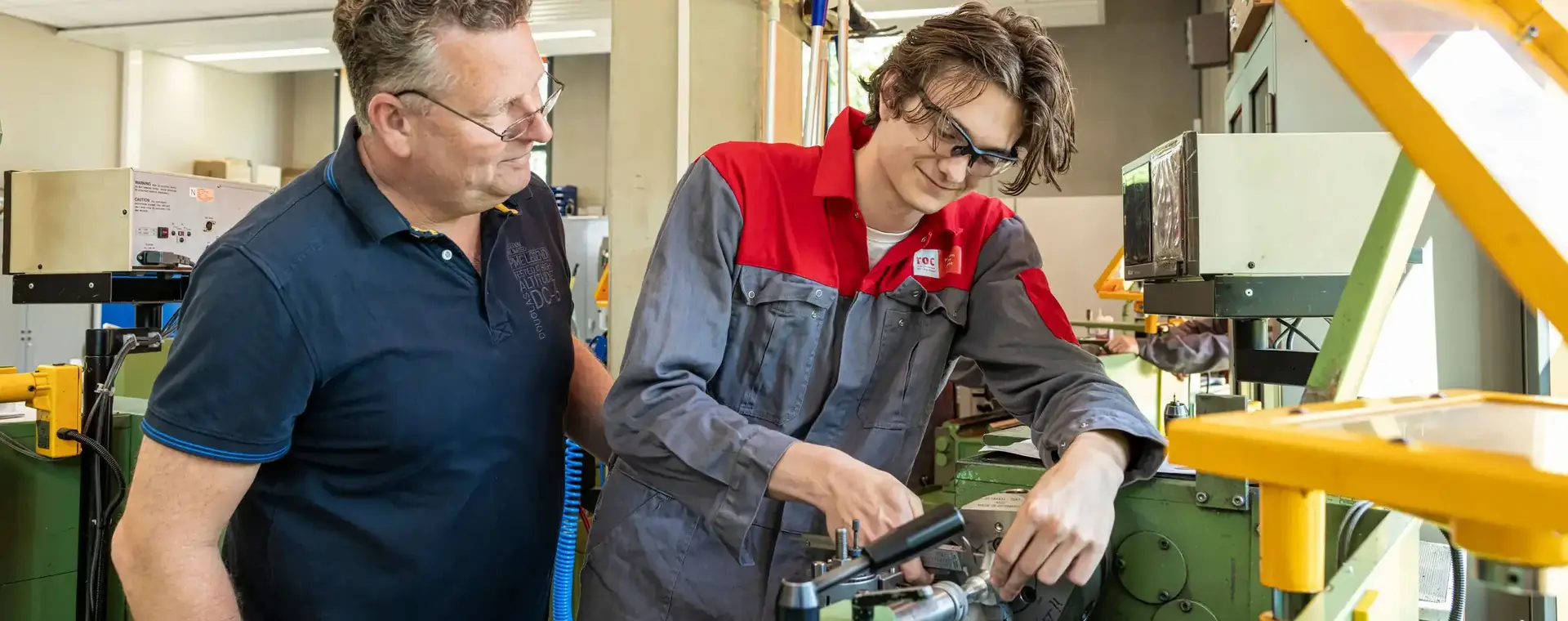 Docent kijkt terwijl student metaal bewerkt door middel van een draaibank