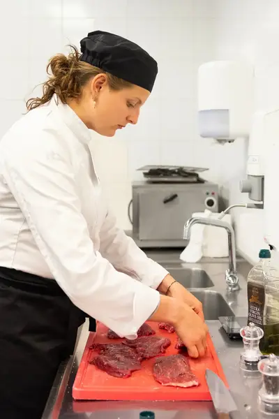 Kok bereidt vlees op snijplank in professionele keuken
