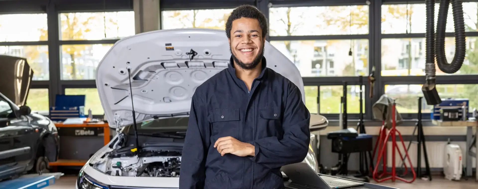 Student automonteur staat voor auto met open motorkap
