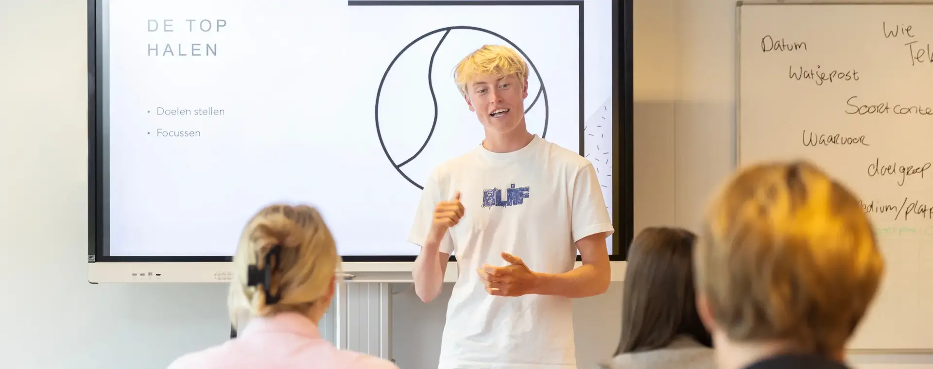 Student in wit T-shirt geeft presentatie in klas