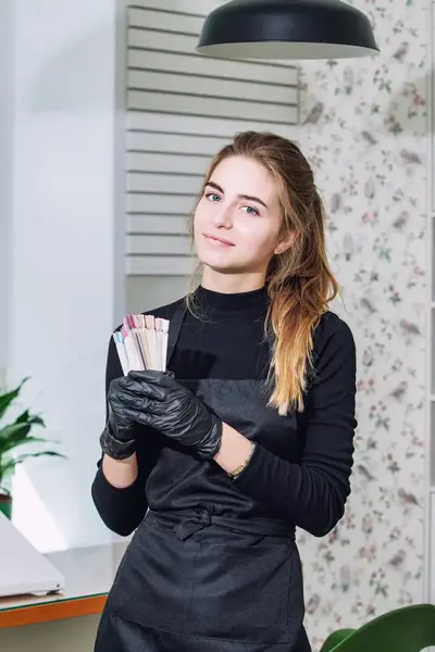 Schoonheidsspecialiste met kleurstalen voor nagels in salon