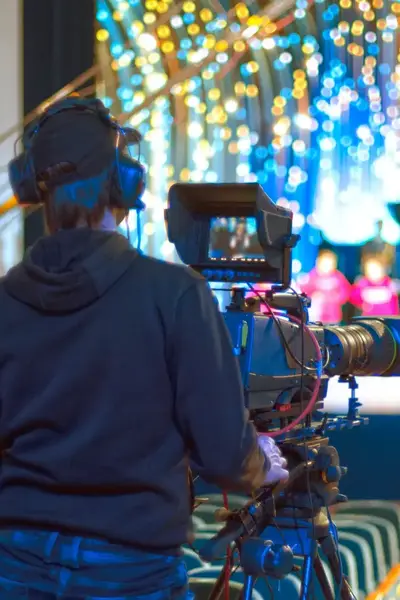Cameraman filmt vanuit de zaal toneelstuk op podium.