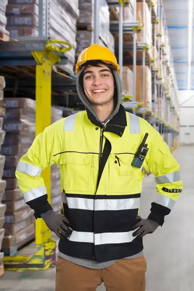 Jongen in gele jas poseert in gang van magazijn.