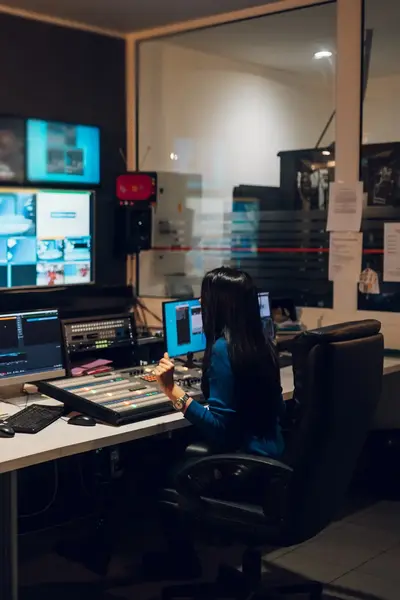 Studente in studio met beeldschermen en geluidspanelen.