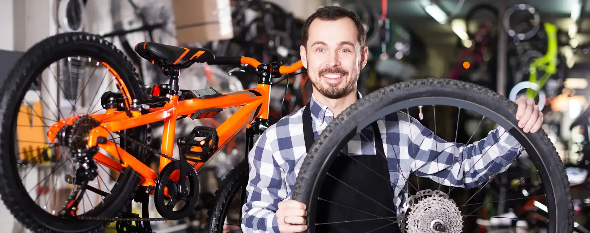 Fietsenmaker tussen fietsen houdt fietswiel vast
