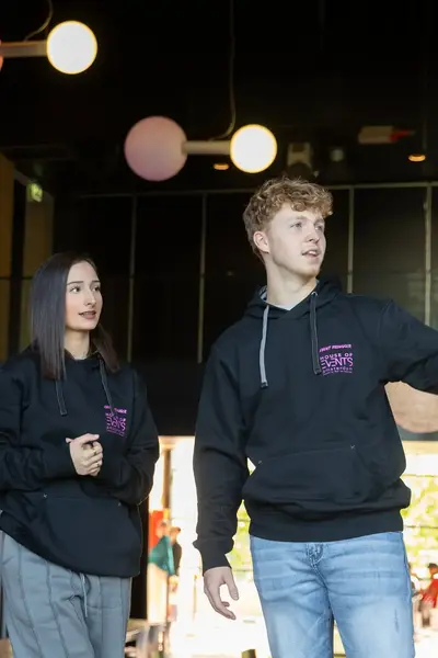 Drie studenten in zwarte sweaters overleggen wat te doen.