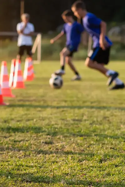Voetballers doen een oefening met voetbal en pionnen tijdens de voetbaltraining.