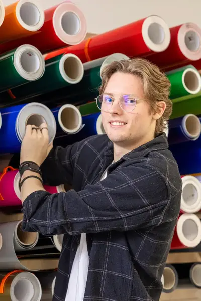 Student haalt blauwe rol uit voorraad gekleurde papierrollen.
