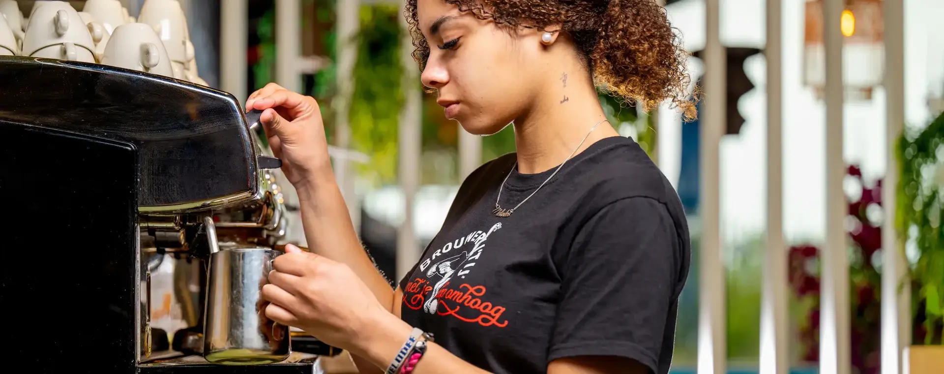 Student maakt koffie met espressomachine tijdens horecaopleiding in Almere Poort.