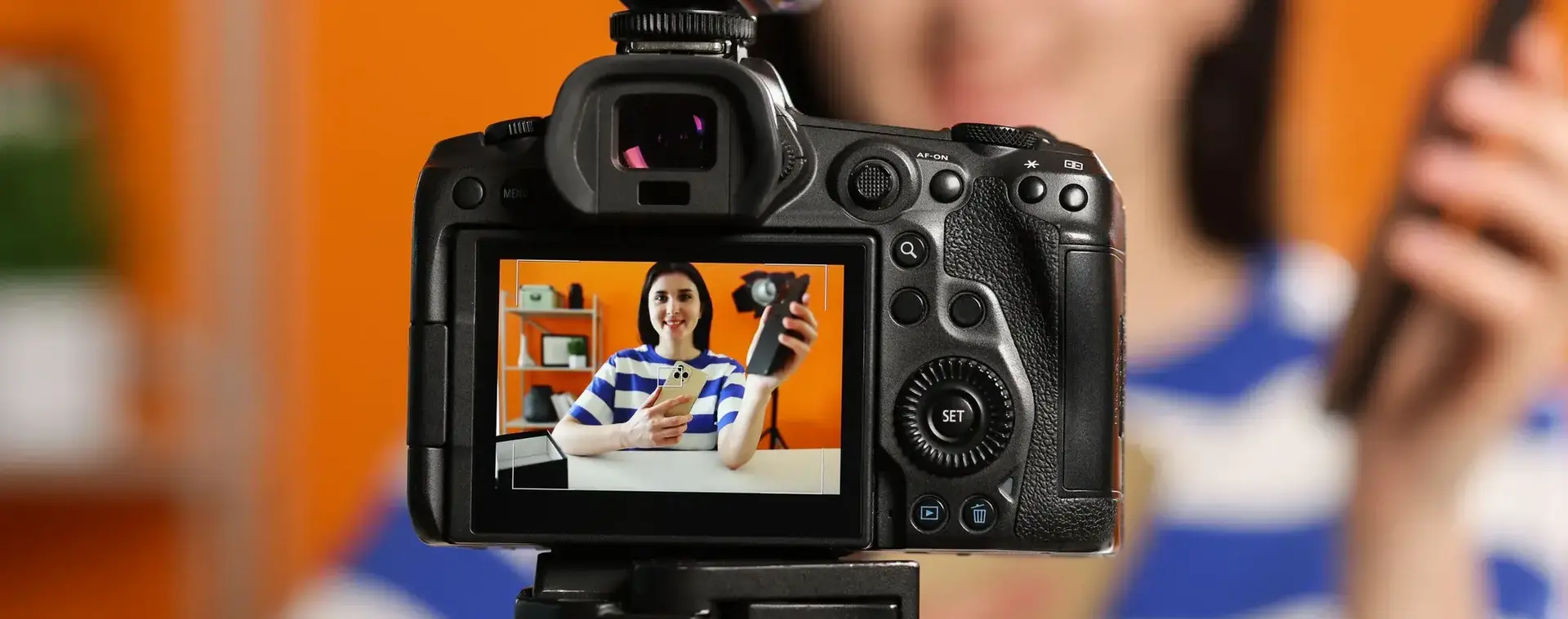 Meisje is met mobiele telefoon en een camera een vlog video van zichzelf aan het maken.