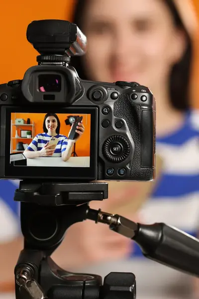 Meisje is met mobiele telefoon en een camera een vlog video van zichzelf aan het maken.