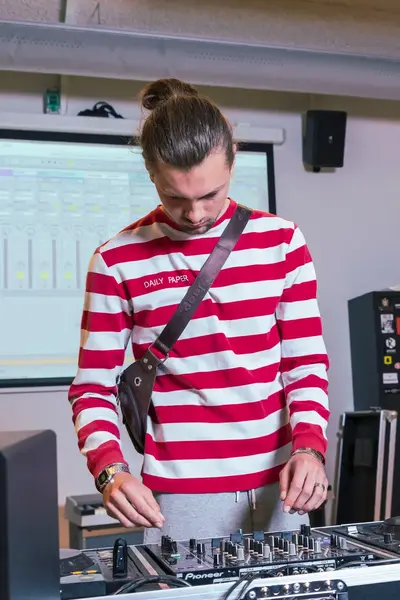 Student oefent met draaien op DJ-apparatuur terwijl een docent meekijkt in een leslokaal.