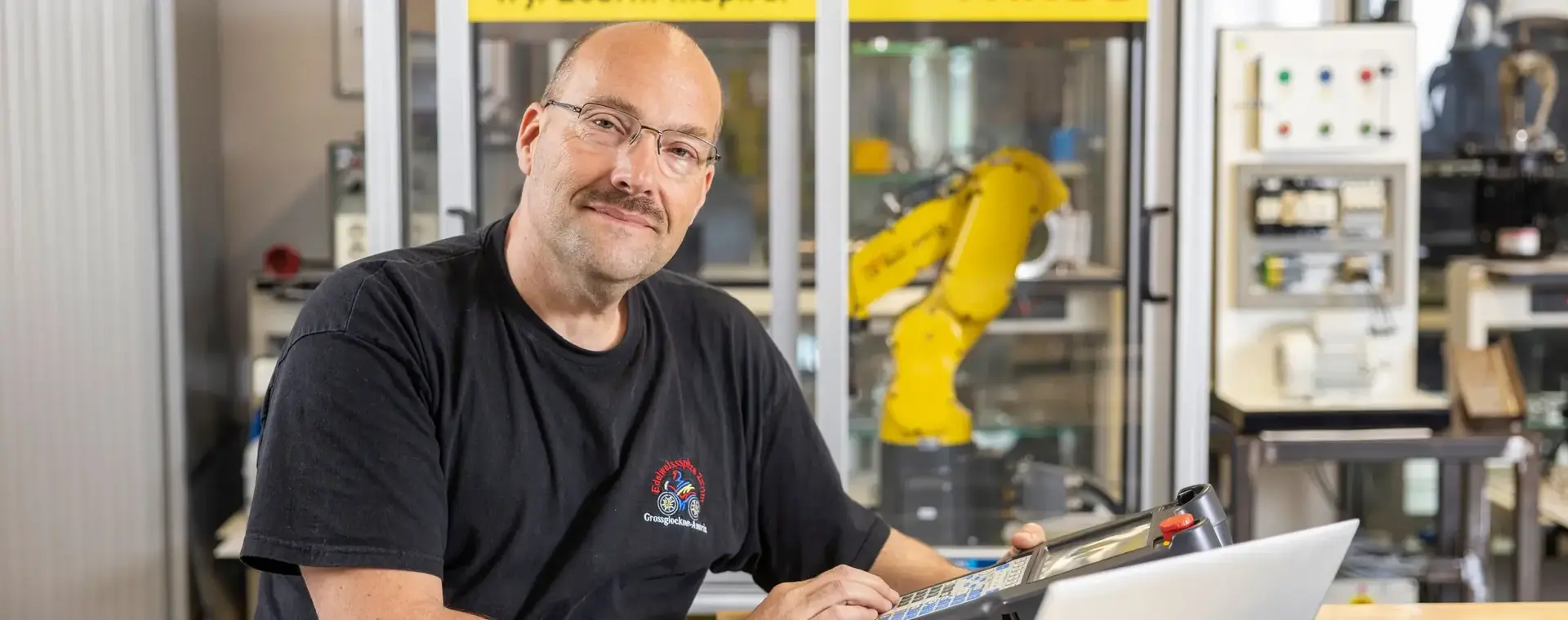 Man met snor tussen elektronische installaties en laptop