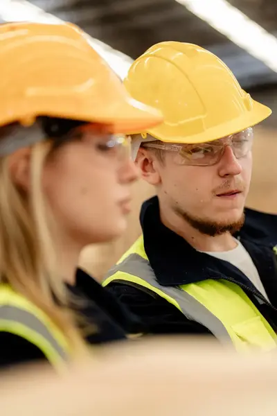 Twee collega's in de bouw met bouwhelmen en gele veiligheidshesjes. 