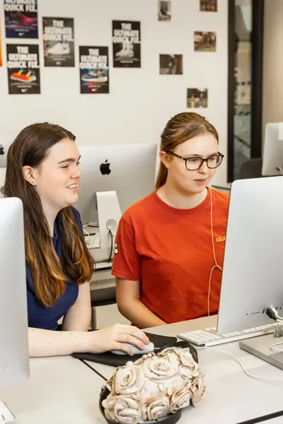 Twee studenten zitten achter een Imac-computer te werken.