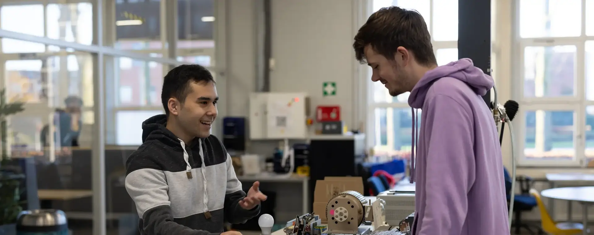 Twee studenten staan bij een technische installatie met lamp