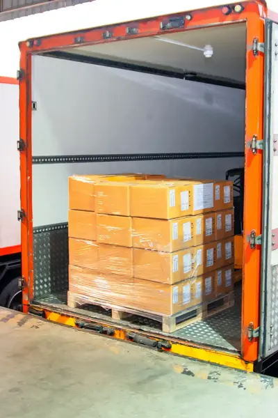 Vrachtwagen met open deuren gevuld met dozen in een distributiecentrum.