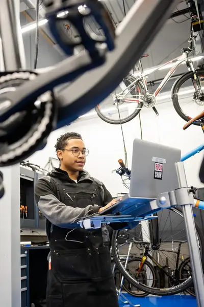 Student in overall achter laptop in fietswerkplaats